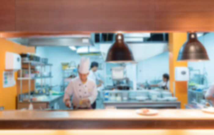 fire suppression kitchen Blurry view of chefs cooking in a restaurant kitchen under warm lighting.